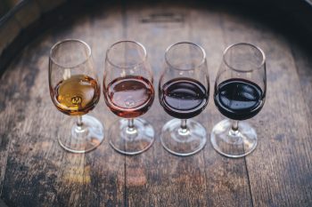Different wine samples displayed on an oak barrel